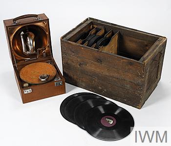 DECCA TRENCH GRAMOPHONE, a selection of the 32 records accompanying the gramophone and the converted ammunition box that housed both the records and the player. Image © IWM copyright, IWM catalogue reference EPH 7660. Original source https://www.iwm.org.uk/collections/item/object/30087341